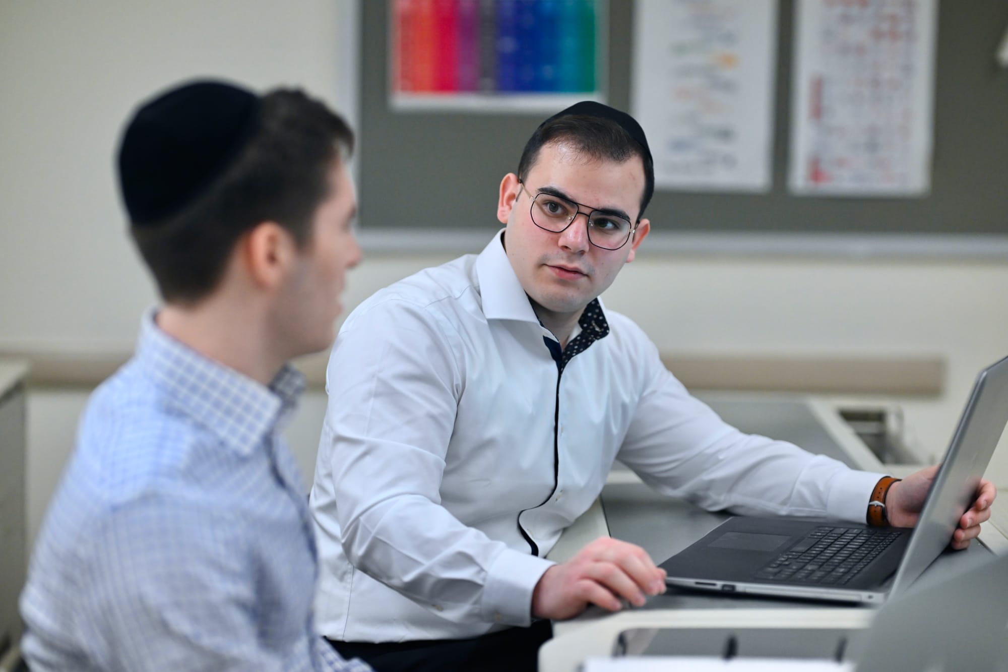 Two male students in professional attire working on laptops