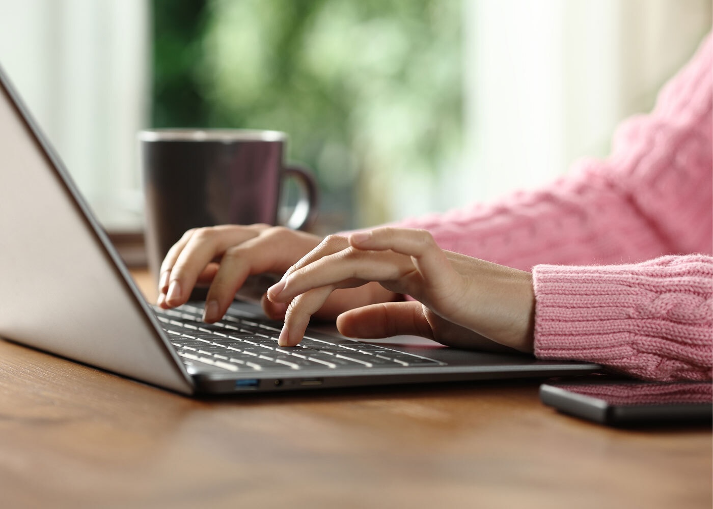 The hands of a woman typing on a computer.